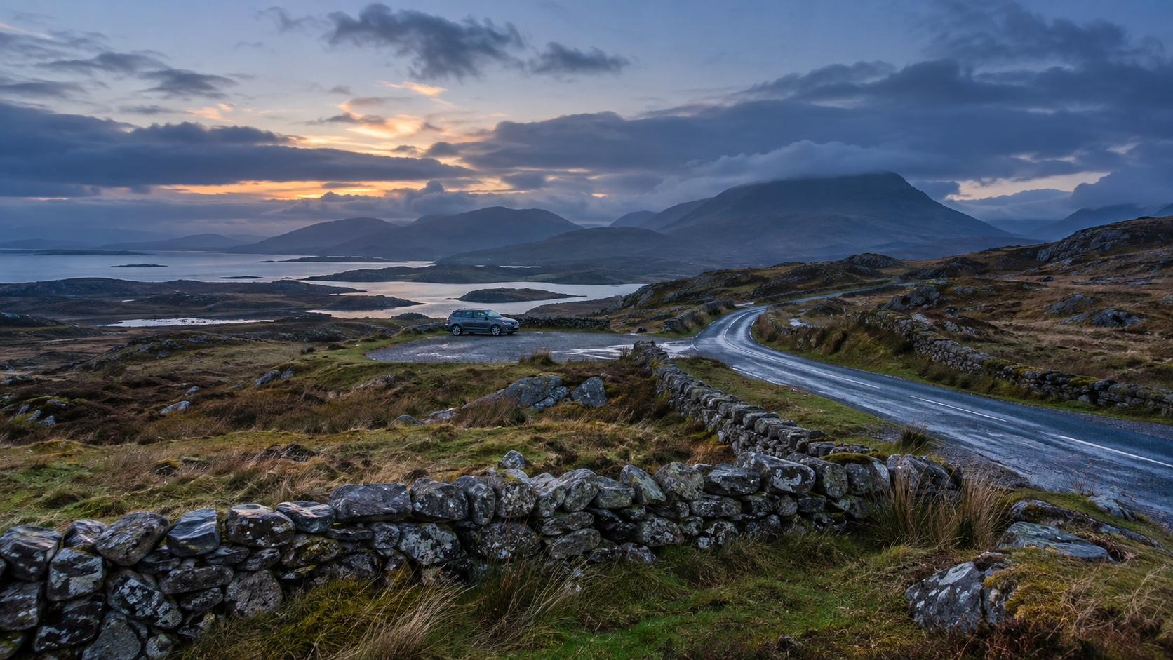 Rain-cleared Connemara road winding through stone-walled coastal mountains at blue hour.
