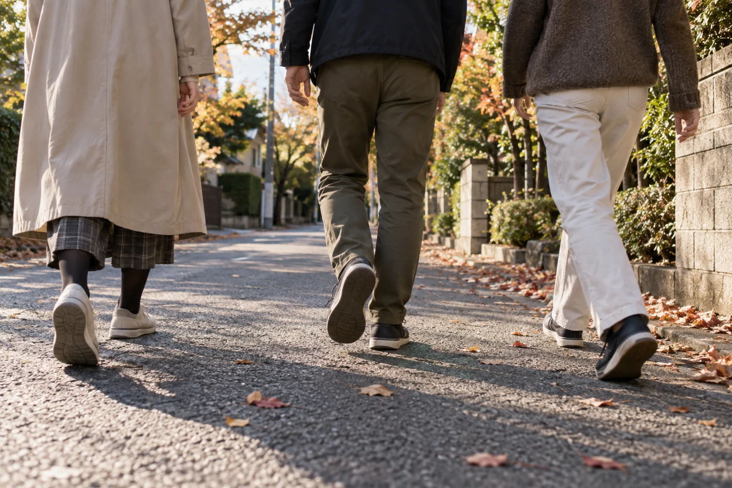 Three adults walking along a quiet residential street, seen from a low angle with faces outside the frame.