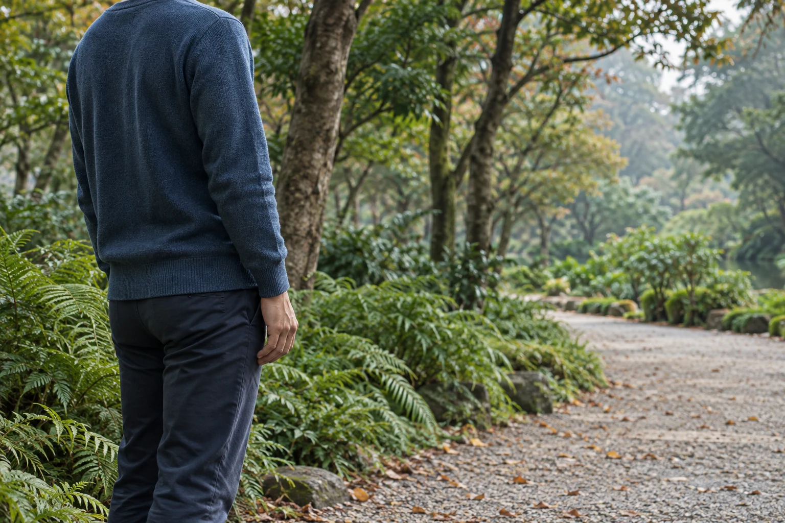 Close view of an anonymous traveler pausing beside a planted Taichung park path.